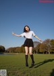 A woman in a school uniform is standing in the grass.