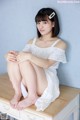 A woman sitting on top of a wooden dresser.