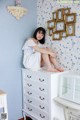 A woman sitting on top of a white dresser.