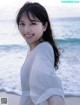 A woman standing on a beach next to the ocean.