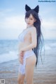 A woman in a white bikini standing on the beach.