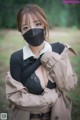 A woman wearing a black face mask in the woods.