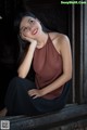 A woman sitting on a window sill with her hand on her chin.