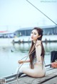 A woman sitting on a dock holding a rope.