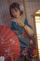 A woman in a kimono holding a red umbrella.