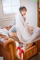 A woman sitting on a brown leather couch wearing a veil.