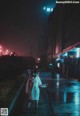 A woman in a white coat is walking down the street at night.