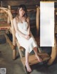 A woman in a white towel sitting on a wooden bench.